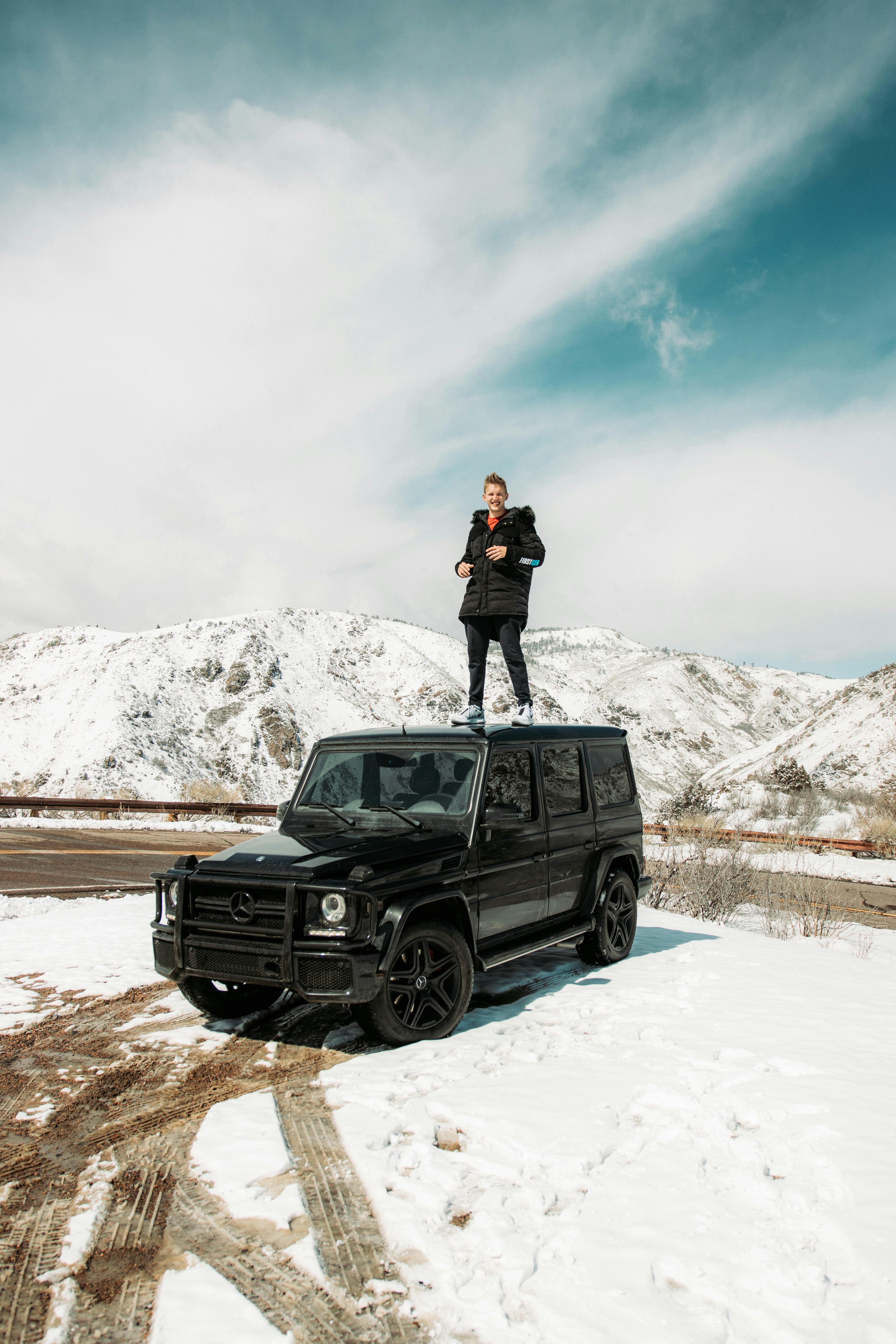 woman in black jacket standing on black suv during daytime